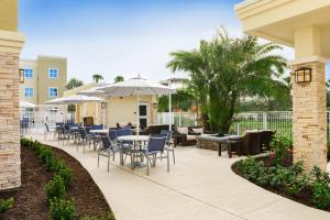 维洛海滩Staybridge Suites - Vero Beach, an IHG Hotel的一个带桌椅和遮阳伞的庭院