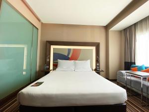 暖武里府曼谷诺富特因帕特酒店的酒店客房设有一张大床和一张沙发。