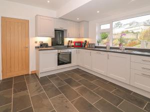 克里基厄斯Nefydd的厨房配有白色橱柜和瓷砖地板。
