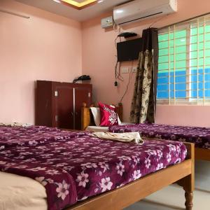 斯里卡拉哈斯蒂Jayaram Residency Srikalahasti的一间卧室配有一张带紫色床单的床和窗户。