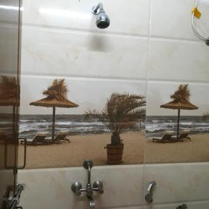斯里卡拉哈斯蒂Jayaram Residency Srikalahasti的浴室拥有海滩的照片,配有椅子和遮阳伞