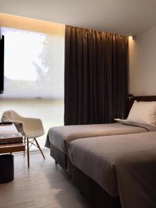 埃尔卡拉法特CASA CHICA的一间卧室设有两张床、一把椅子和一个窗户。