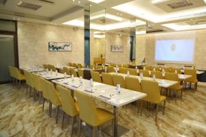 布赖代Brand Al Qassim Hotel的一间会议室,配有桌椅和投影屏幕