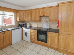 BallymoteDuffy's Cottage的厨房配有木制橱柜、洗衣机和烘干机