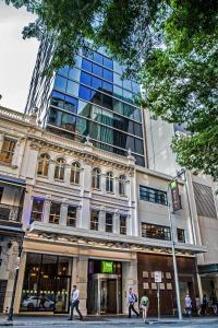 布里斯班ibis Styles Brisbane Elizabeth Street的一座高大的建筑,前面的人在步行