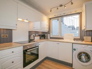 埃尔金The Neuk的厨房配有白色橱柜、洗衣机和烘干机
