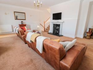 北希尔兹Tynemouth Village Penthouse的客厅配有棕色真皮沙发和壁炉
