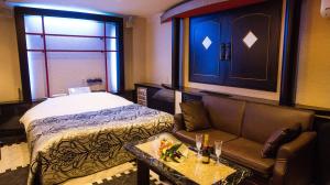 函馆樱花再住酒店（仅限成人）的客房设有床、沙发和桌子。