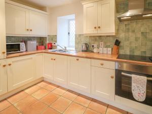 CaledonRobertson's Cottage的厨房配有白色橱柜和瓷砖地板。