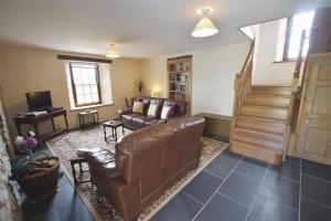 GoodwickPanteurig Farmhouse的客厅设有棕色皮革沙发和楼梯。