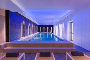 卡尔卡松Hotel du Roi & Spa by SOWELL COLLECTION的蓝色瓷砖建筑中的游泳池