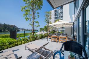 邦涛海滩Cassia Residences by Laguna Phuket的庭院配有桌椅和遮阳伞。