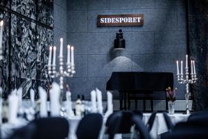 霍尔拜克希德斯博安酒店的用餐室配有带蜡烛的桌子和钢琴