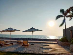 纳仲天Veranda Residence by VS的海滩上设有椅子和遮阳伞,还有大海