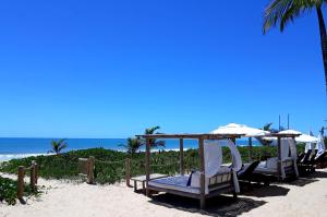 托兰克索Hotel e Resort Villas de Trancoso的海滩上的一组椅子和遮阳伞