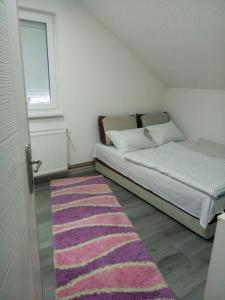 萨拉热窝Apartman All seasons的一间小卧室,配有一张床和粉红色的地毯