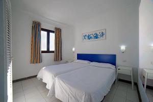 卡门港蓝色广场酒店的一间卧室配有一张大床和蓝色床头板