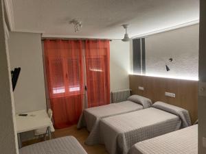 萨拉曼卡Hostal Uría的一间卧室设有两张床和红色窗帘