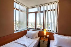 扬博尔Panorama Top Floor Rooms in Hotel Tundzha的一间卧室设有两张床和大窗户