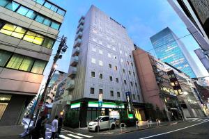 东京名铁滨松酒店 的城市街道上一座高大的白色建筑,有建筑