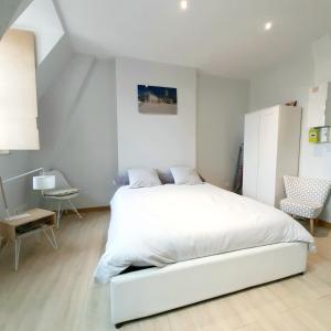 第戎Studio Jean LEBELIN的白色卧室配有白色的床和椅子