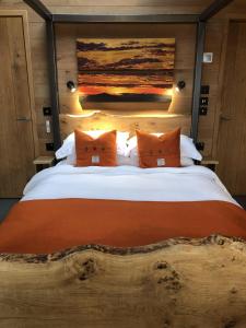 BreakishArdcana的一间卧室配有一张带橙色枕头的大型木制床。