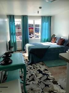 科迪亚克Aquamarine Suites的一间卧室配有一张带蓝色窗帘的床和一张桌子