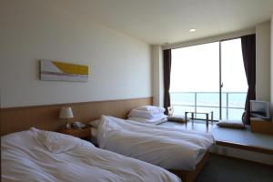 米子市Bayside Square Kaike Hotel的酒店客房设有两张床和一个阳台。