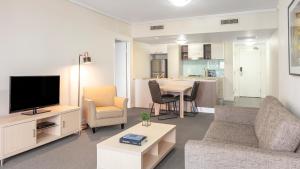 布里斯班Oaks Brisbane on Charlotte Suites的带沙发、电视和桌子的客厅