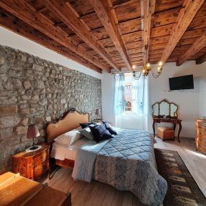 弗留利地区奇维达莱B&B Domus iulii的一间卧室设有一张床和石墙