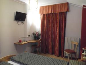 利维尼奥阿黛尔酒店的客房设有床、书桌和电视。