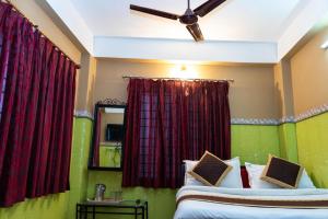 西里古里Tirupati Lodge NJP的一间卧室设有两张床和红色窗帘