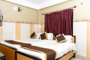 西里古里Tirupati Lodge NJP的红色窗帘间内的两张床