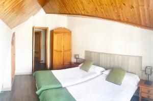 塞拉内华达Apartamentos Sabica Nevada Plaza的一间卧室配有一张带白色床单和绿色枕头的大床。