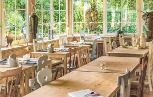 辛佩尔费尔德Pet Friendly Home In Simpelveld With Outdoor Swimming Pool的餐厅设有木桌、椅子和窗户。