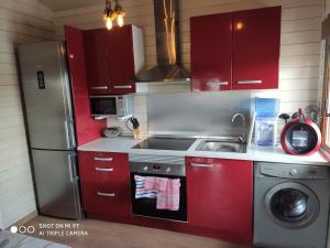 TorrellesCasa Ecoeficiente Eguzkilore的厨房配有红色橱柜和不锈钢冰箱