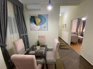 开罗Maspero Nile View Serviced Apartments by Brassbell的一间设有玻璃桌和粉红色椅子的用餐室