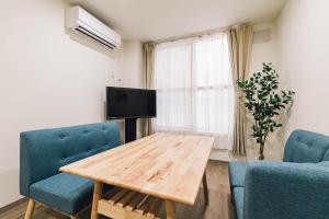 旭川TKD HOUSE Asahikawa的客厅配有木桌和蓝色椅子