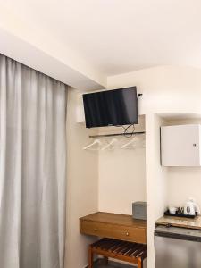 法里拉基奥米洛斯酒店的一间设有挂在墙上的电视及窗帘的房间