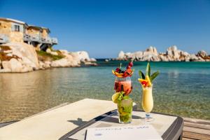 博尼法乔Hotel & SPA des Pecheurs的坐在水边的桌子上喝两杯鸡尾酒