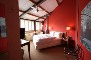 图贝尔亨德罗斯特赫伯格酒店的一间卧室设有一张床和红色的墙壁