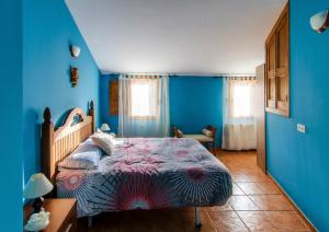 圣马尔廷德特雷韦霍Casa Rural Las 6 Hermanas的一间拥有蓝色墙壁的卧室和一张位于客房内的床
