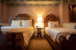 杜兰戈The Strater Hotel的一间卧室配有两张床和一张带台灯的桌子