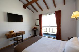 库斯科DM Hoteles Cusco的一间卧室配有一张床、一张书桌和一个窗户。