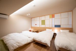 金泽marutto Ishikawa的配有白色床单的客房内的两张床
