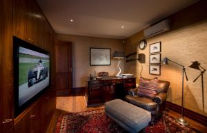 格拉罕镇Kwandwe Fort House的客厅配有平面电视和椅子。