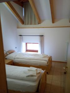 Pieve Tesino塔克斯旅舍的客房设有两张床和窗户。