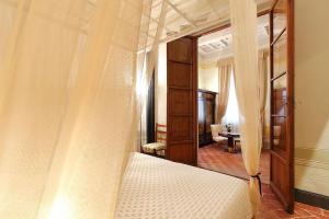 佛罗伦萨乌菲兹哈莫尼旅馆的一间卧室配有一张带镜子的天蓬床