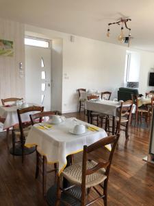 CuremonteLe Moulin de Lassalle的用餐室配有白色的桌子和木椅
