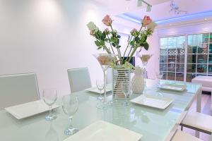 巴达洛纳Kamelly的一间用餐室,配有带花卉的花瓶玻璃桌